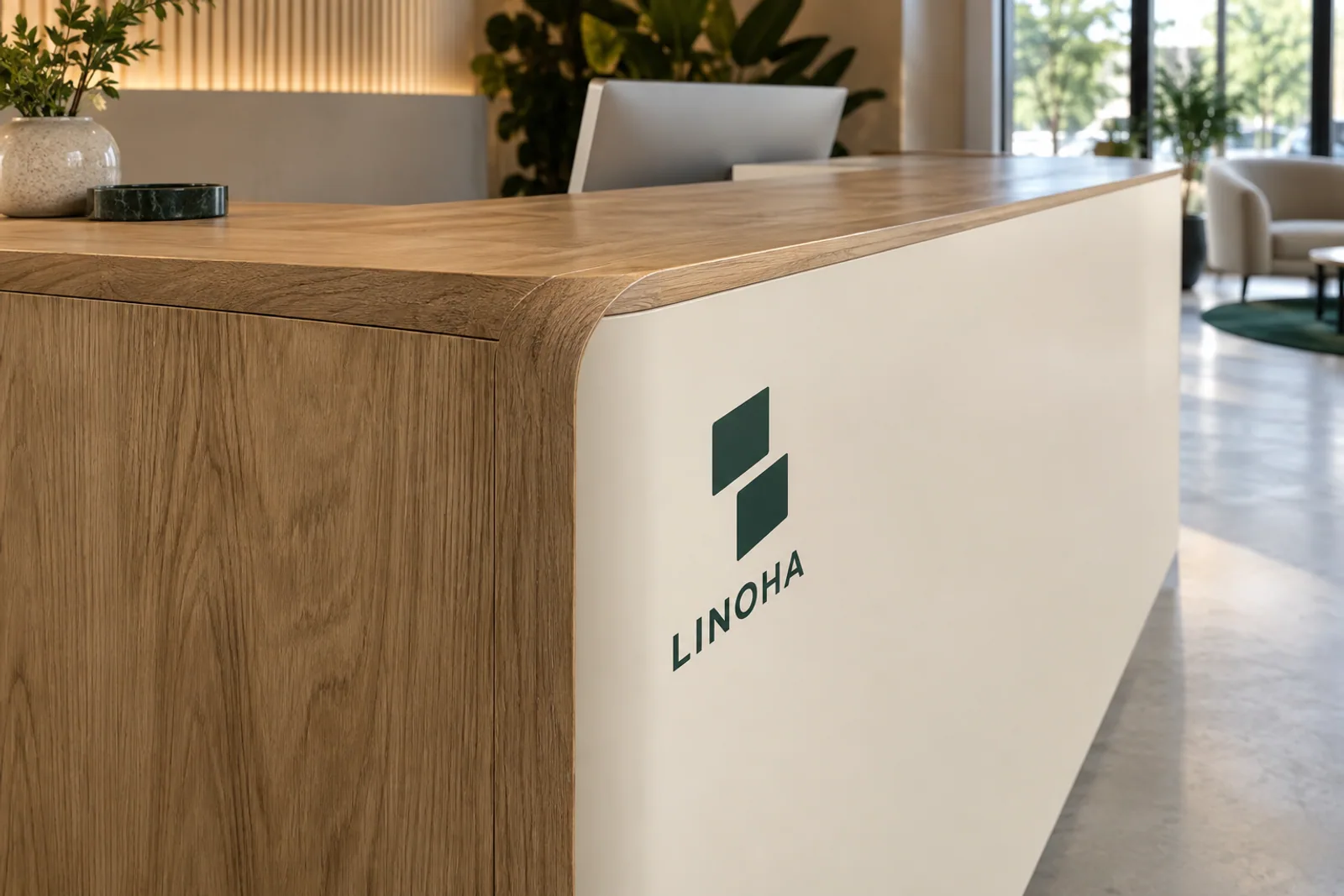 Abgerundete Ecke eines Empfangstresens in Eiche-Optik mit cremefarbener Front und dunkelgrünem LINOHA-Logo.