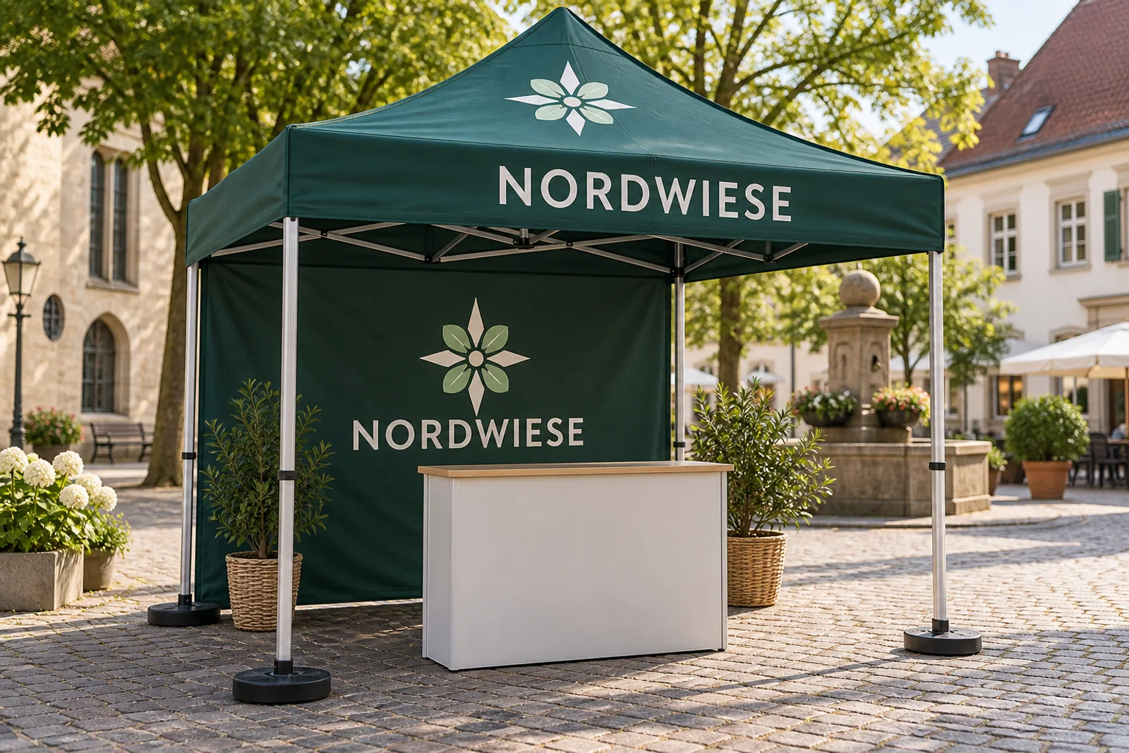 Dunkelgrüner NORDWIESE-Pavillon mit bedrucktem Dach, Rückwand, sichtbarem Gestänge und beschwerten Füßen auf einem gepflasterten Platz.