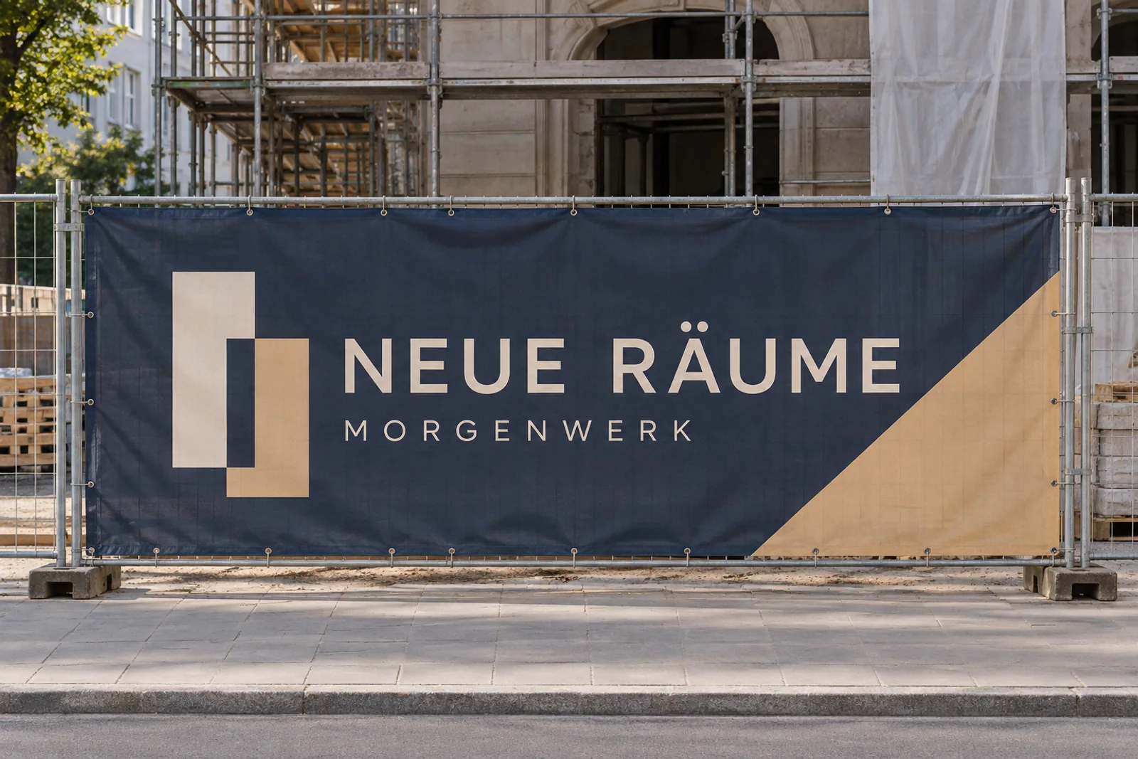 Dunkelblaues Bauzaunbanner „NEUE RÄUME – MORGENWERK“ mit sandfarbenen Formen vor einem eingerüsteten Gebäude.