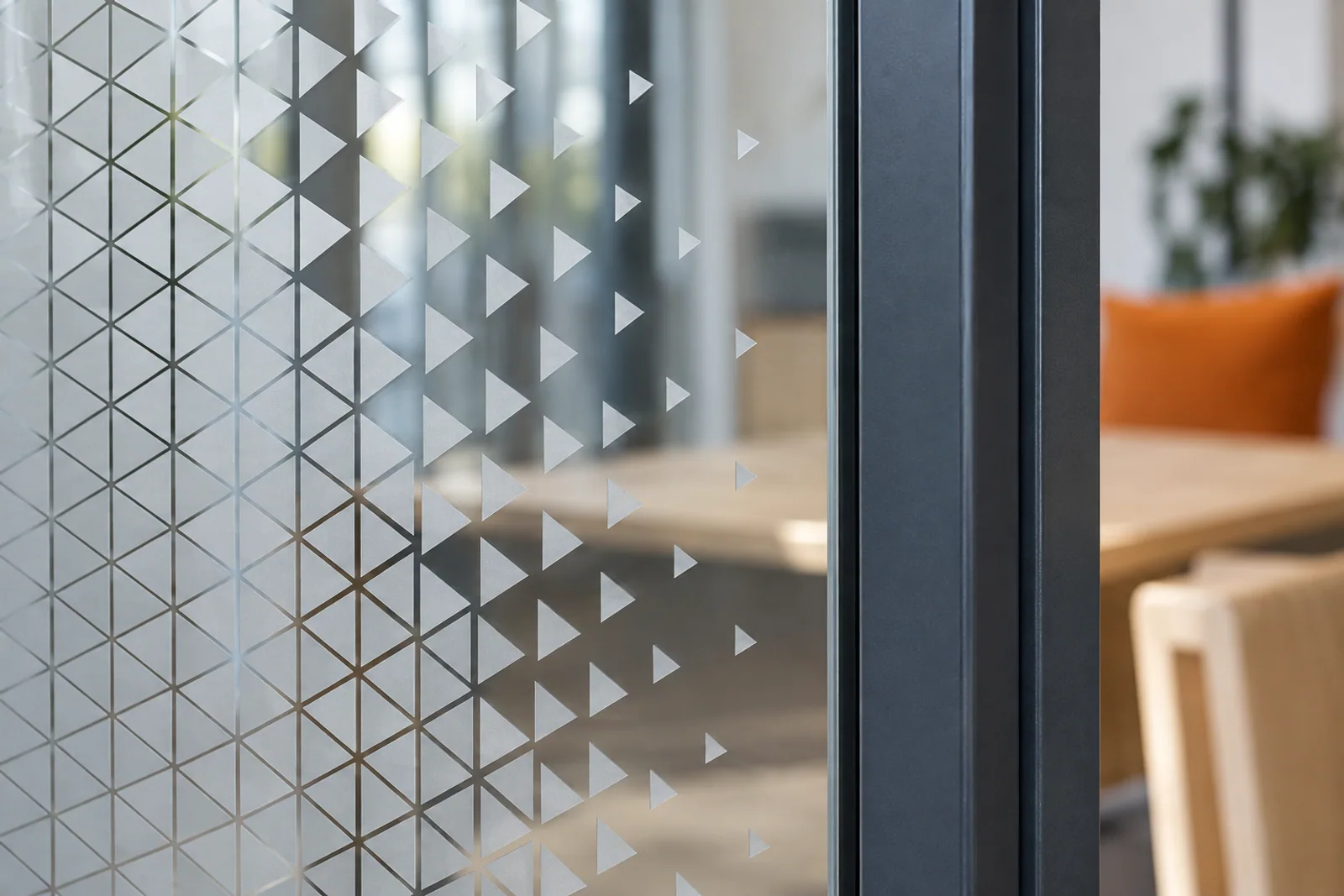 Geometrische Glasdekorfolie mit auslaufendem Dreiecksmuster neben einem dunklen Türrahmen.