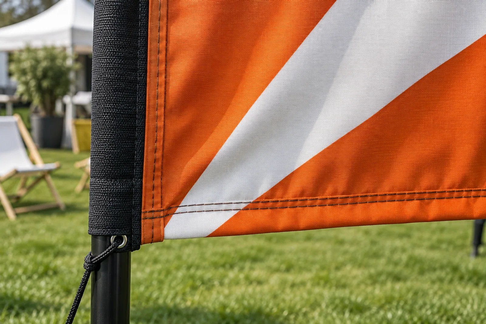 Detail einer orange-weißen Beachflag mit Doppelnaht, verstärktem Mastsaum und Spannkordel.