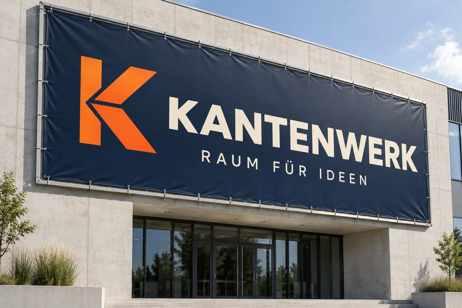 Großes dunkelblaues Fassadenbanner „KANTENWERK – RAUM FÜR IDEEN“ mit orangefarbenem Winkelsignet in einem Aluminium-Spannrahmen über einem Eingang.
