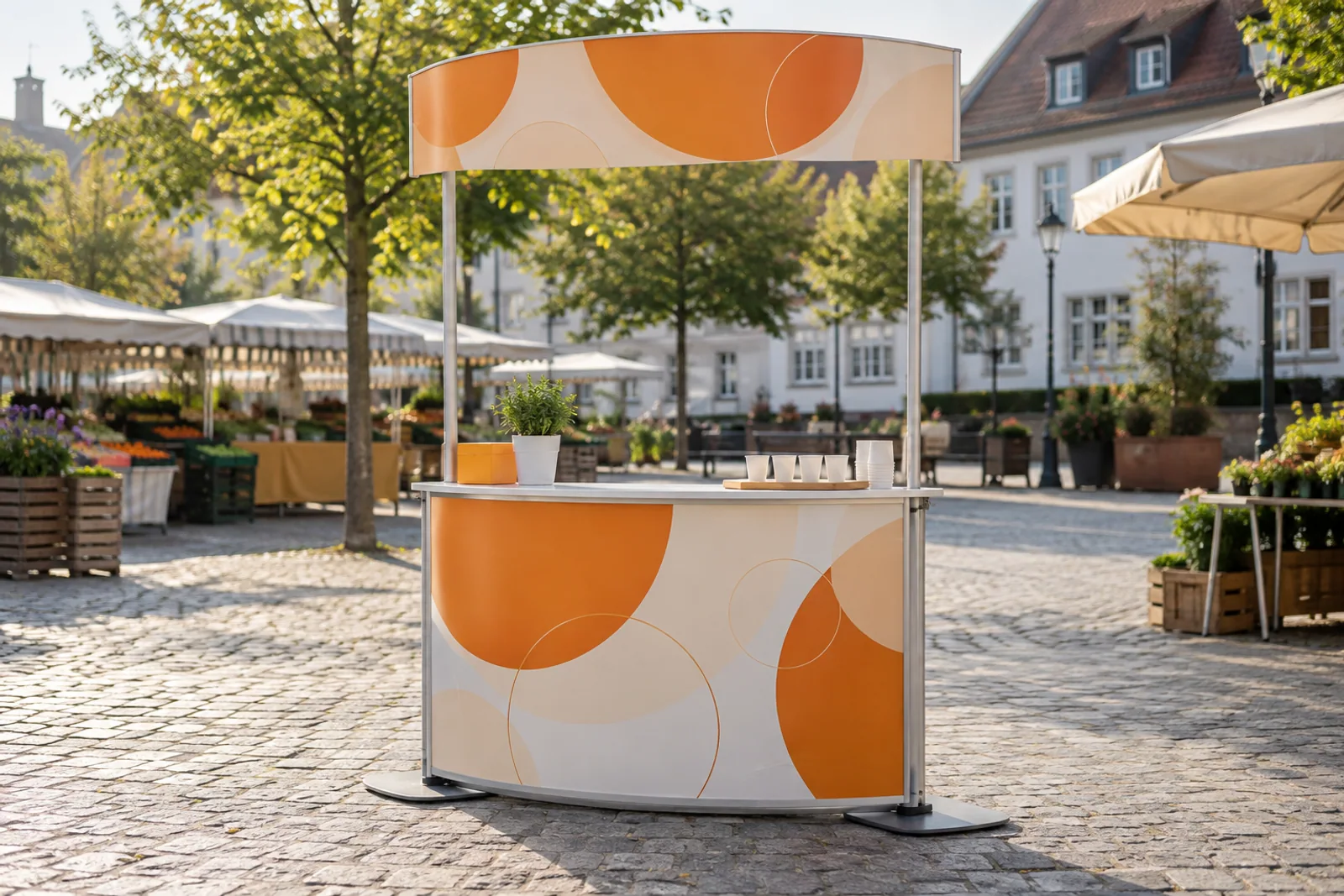 Orange-weißer Promotioncounter mit hohem Kopfschild auf einem Marktplatz.