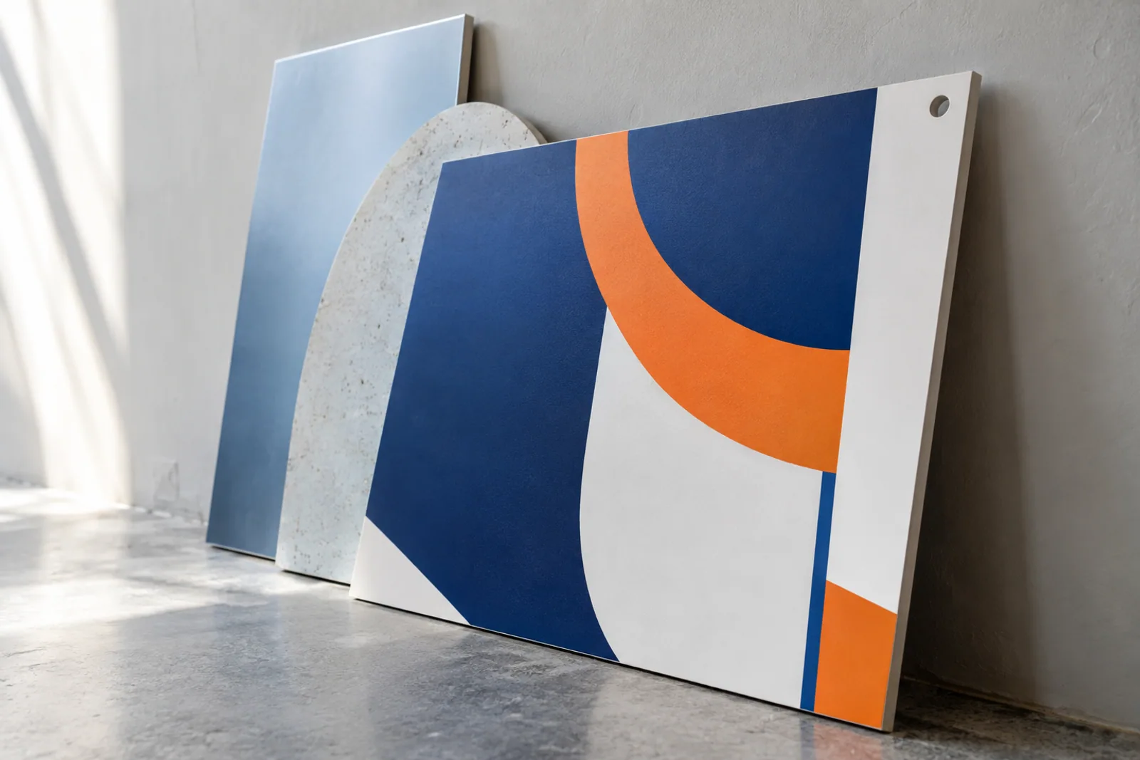 Starre bedruckte Platten mit sichtbaren Kanten und blau-orangefarbenen Grafiken an einer Studiowand.